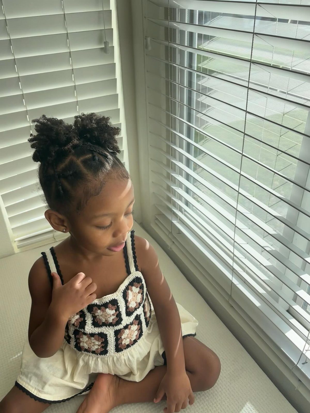 Young Black girl with cornrows styled into two small braided buns on top.