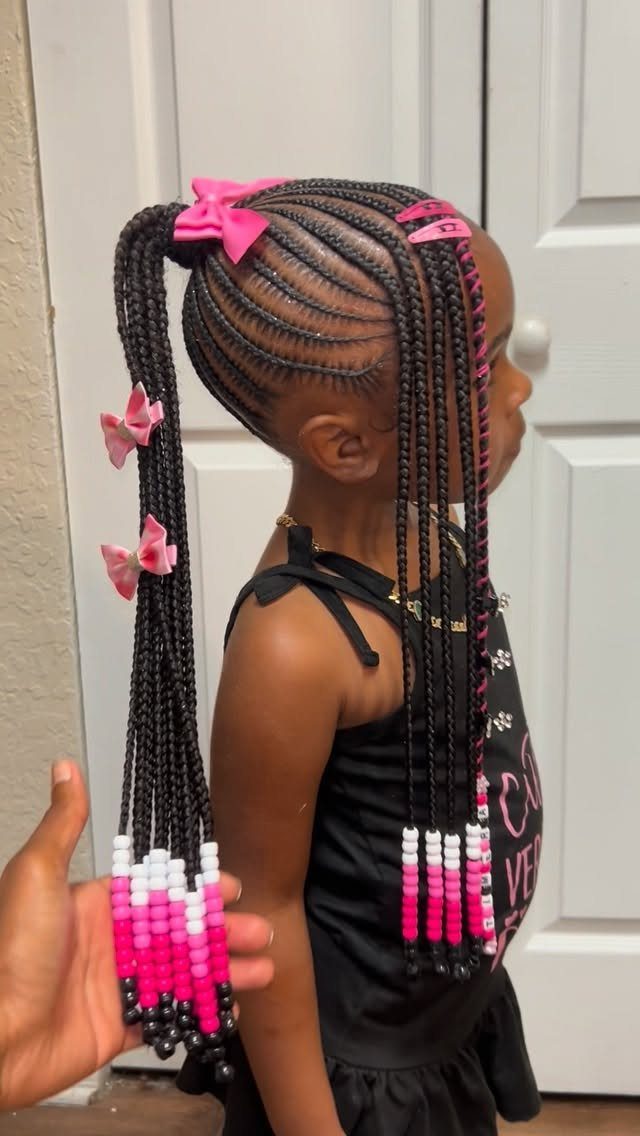 Young girl with cornrow braids decorated with pink bows and colorful beads.