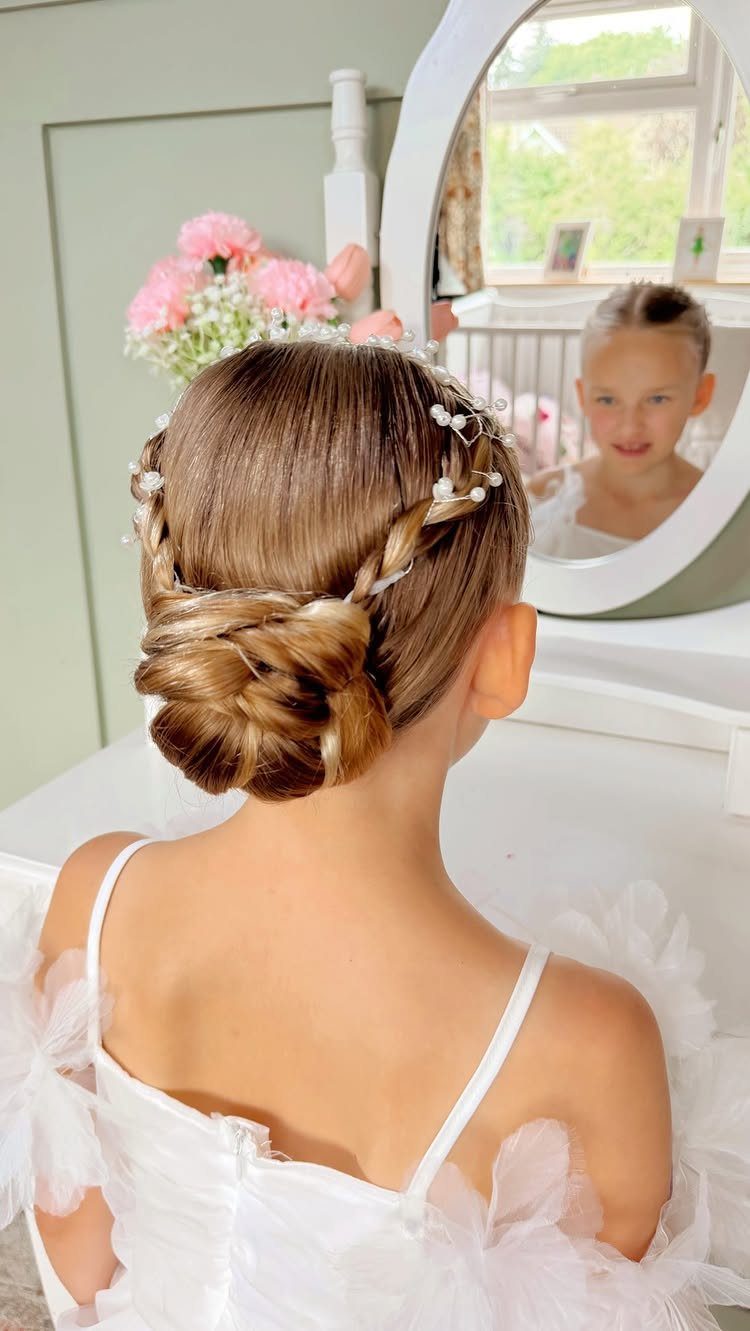 Young girl with blonde braided hair and pearls looking into a mirror