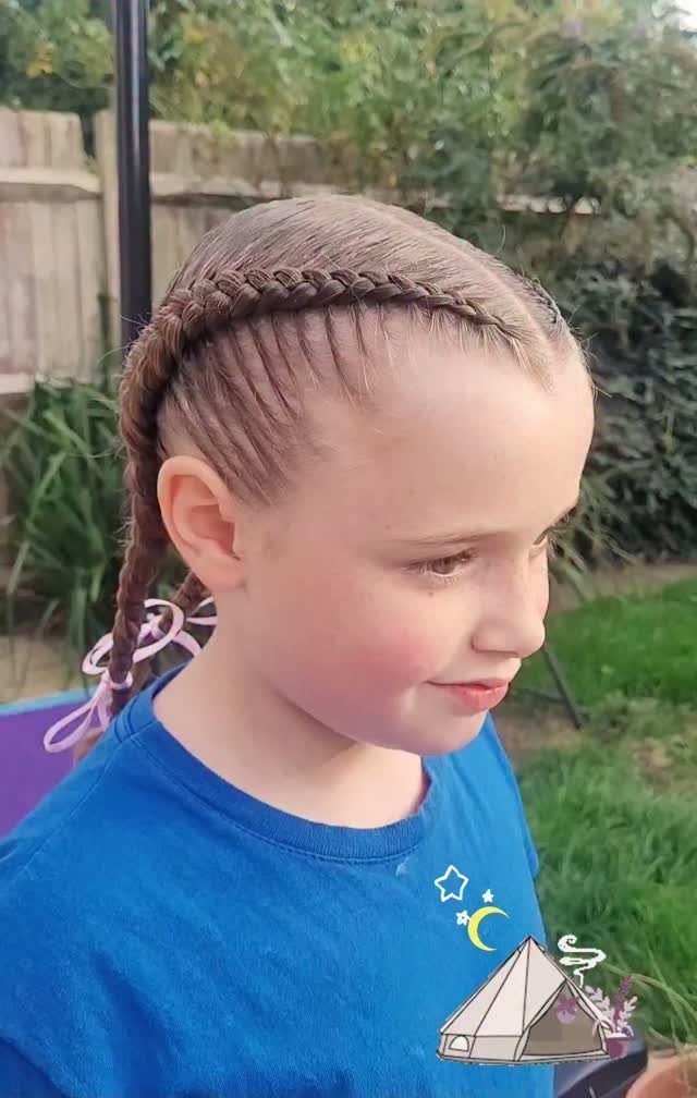 Young girl with a side Dutch braid and pink ribbon wearing blue shirt