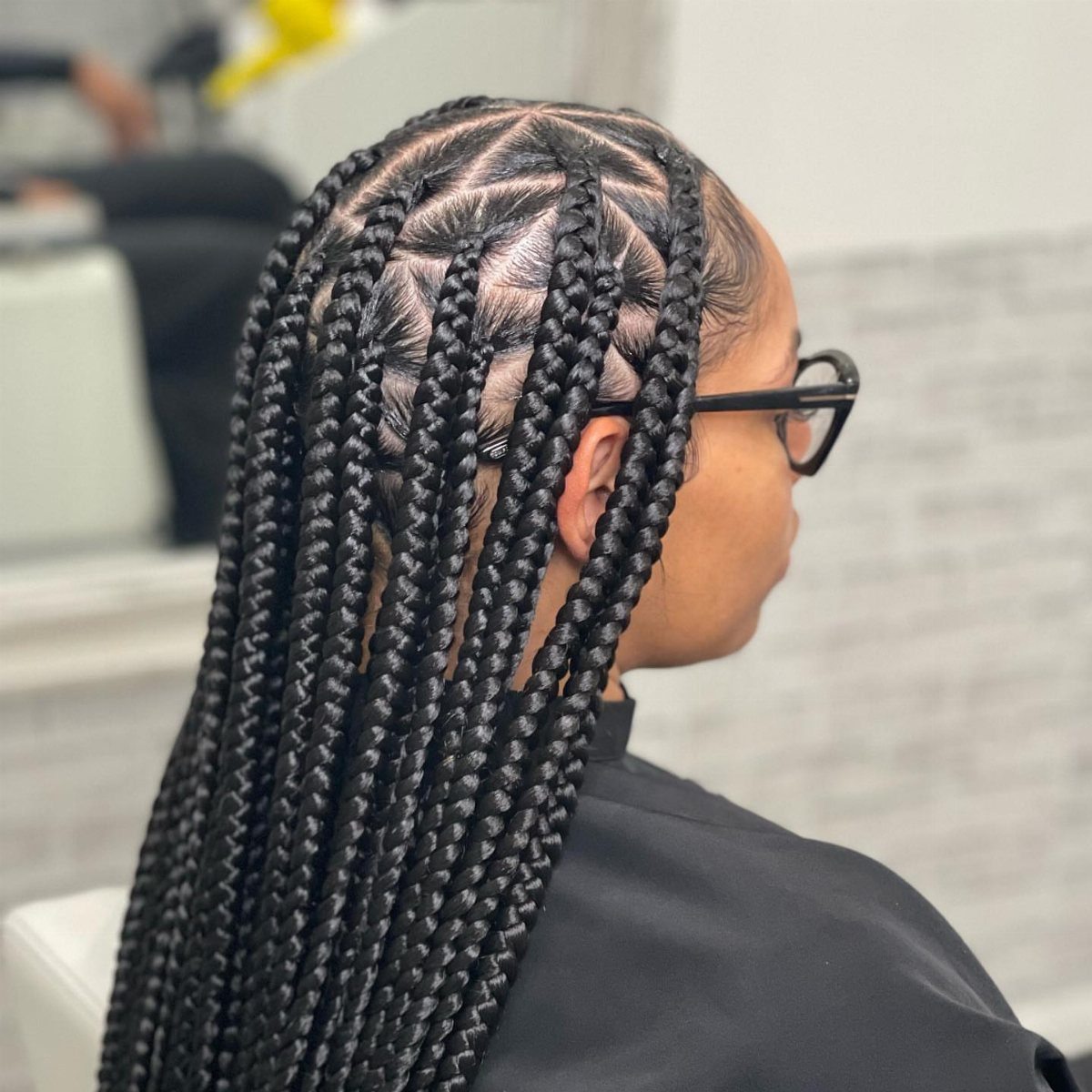 Long black box braids with precise triangle scalp parts on a person.