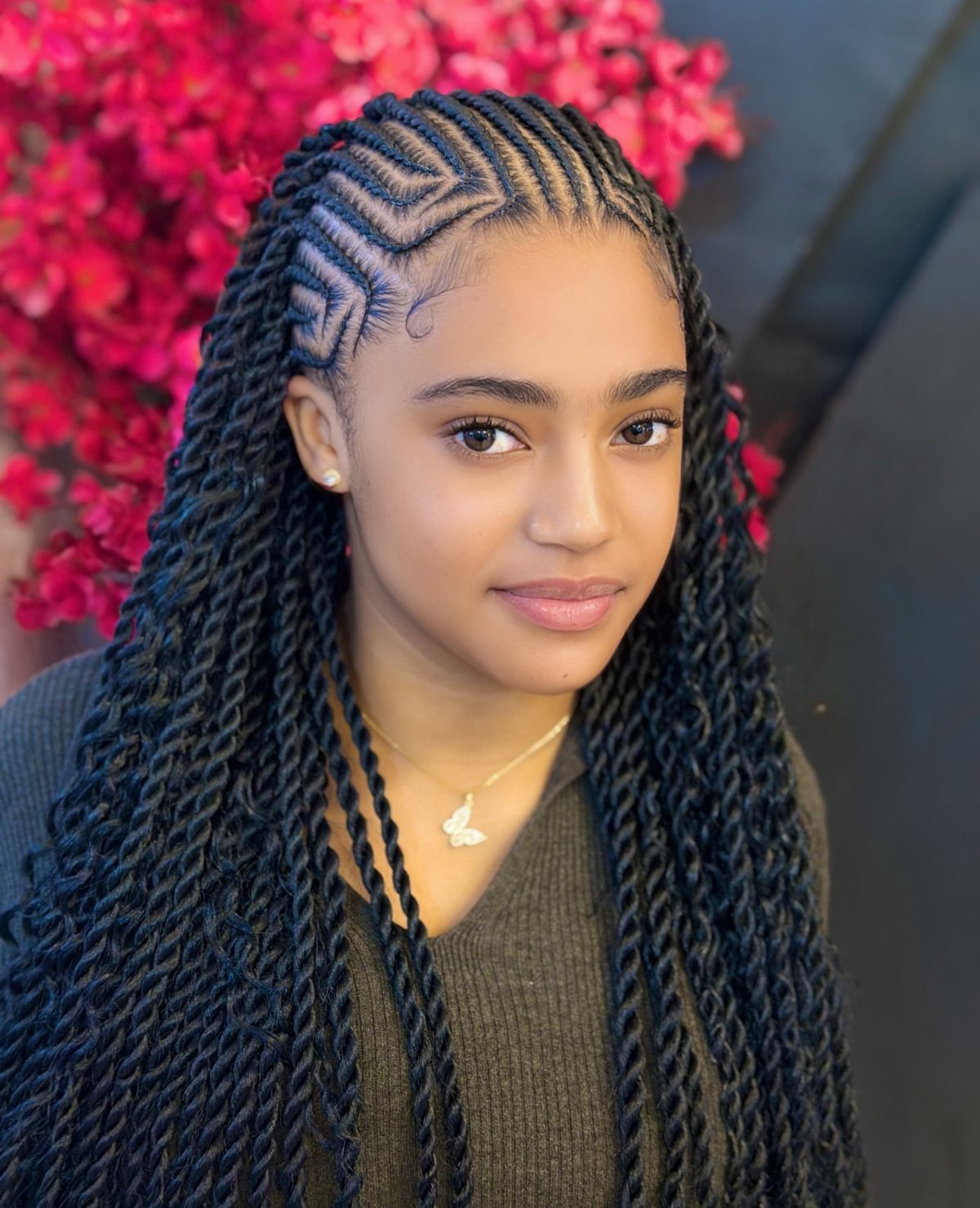 Young girl with long black twisted braids and geometric scalp braiding patterns.
