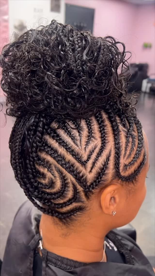 Intricate curved cornrow braids leading into a large curly bun on top.