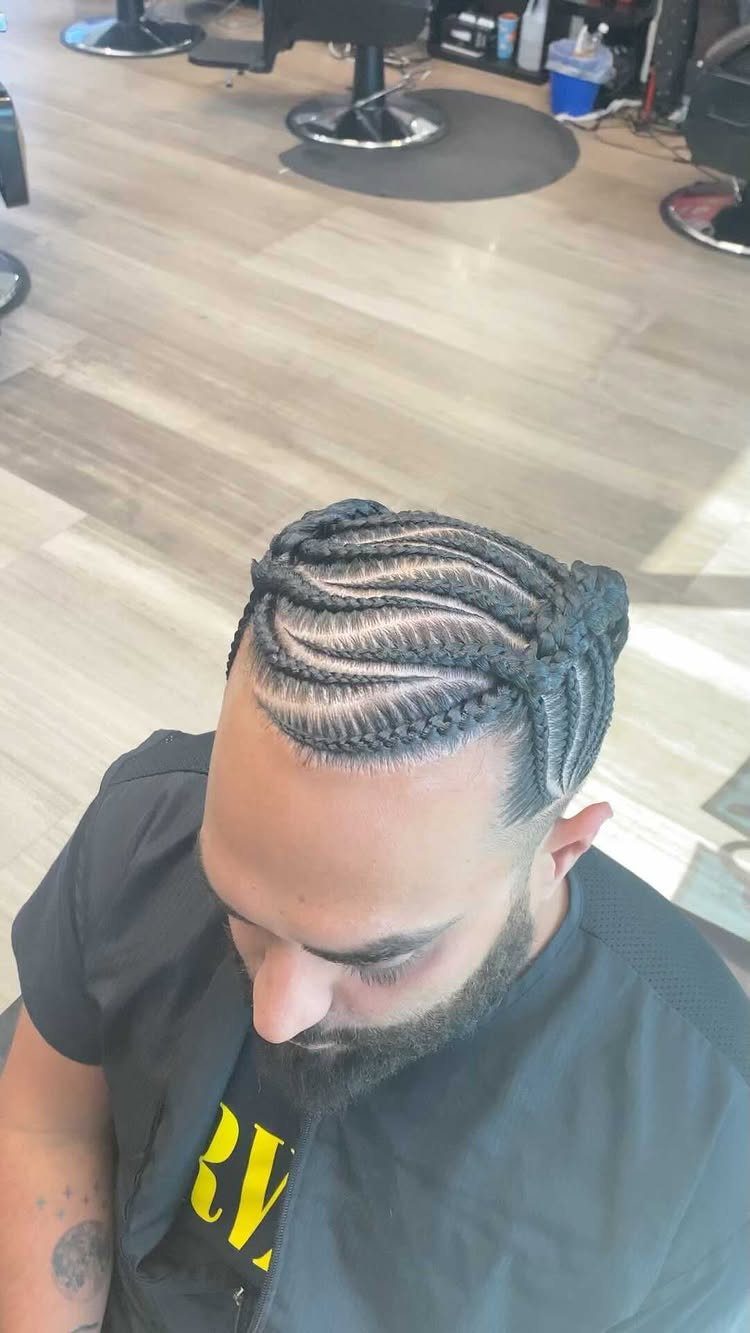 Man with intricate cornrow braids and a fade in a barbershop setting