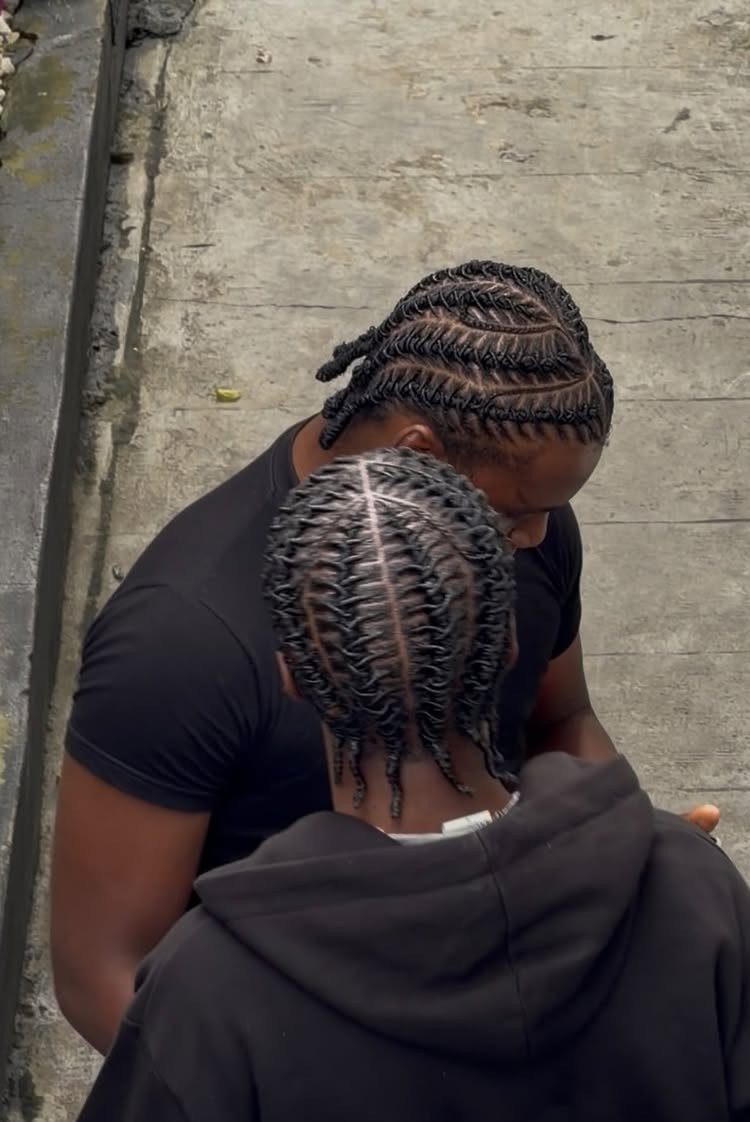 Two men with neat cornrow braids seen from a high angle outdoors.