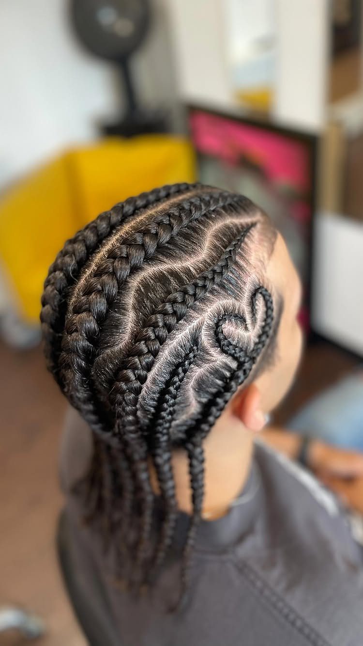 Man with intricate cornrow braids featuring curved patterns and a heart design.