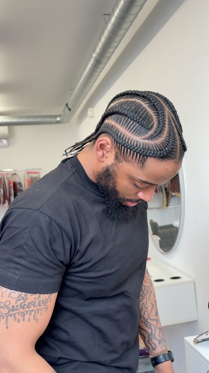Man with a beard showing off a precise stitch braid hairstyle with curved parts.