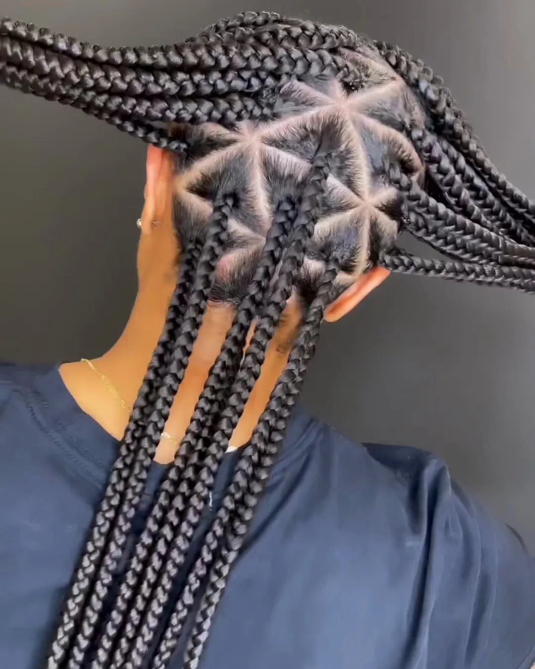 Black box braids with a geometric triangle parting pattern on the scalp.