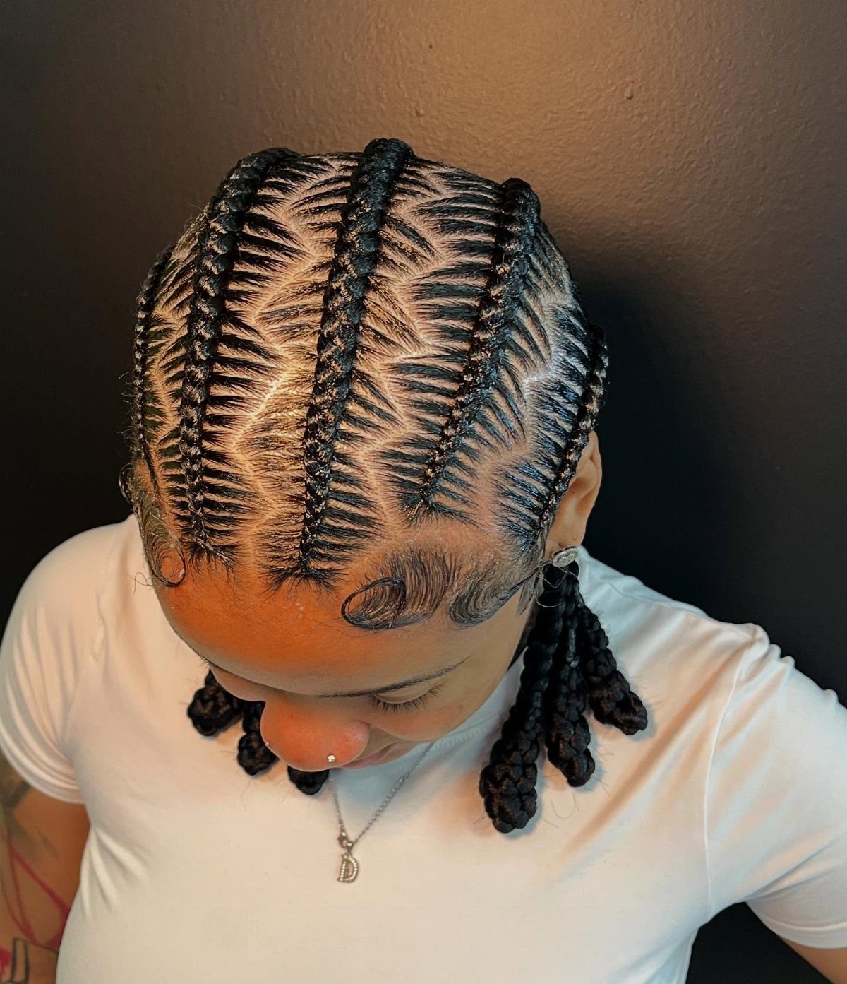 Person with black hair styled in cornrows featuring intricate zig-zag parting patterns.