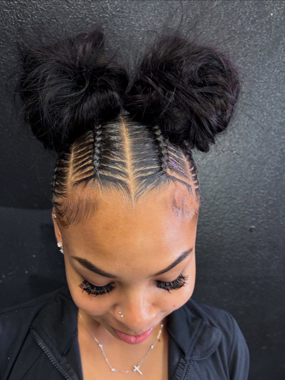 Woman with cornrow braids leading into two large, fluffy black space buns.