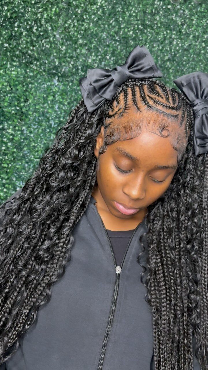 Woman with Fulani braids and black satin bows against a green hedge background