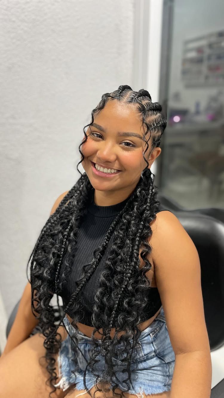 Woman with long black Ghana braids and curly ends smiling in a room