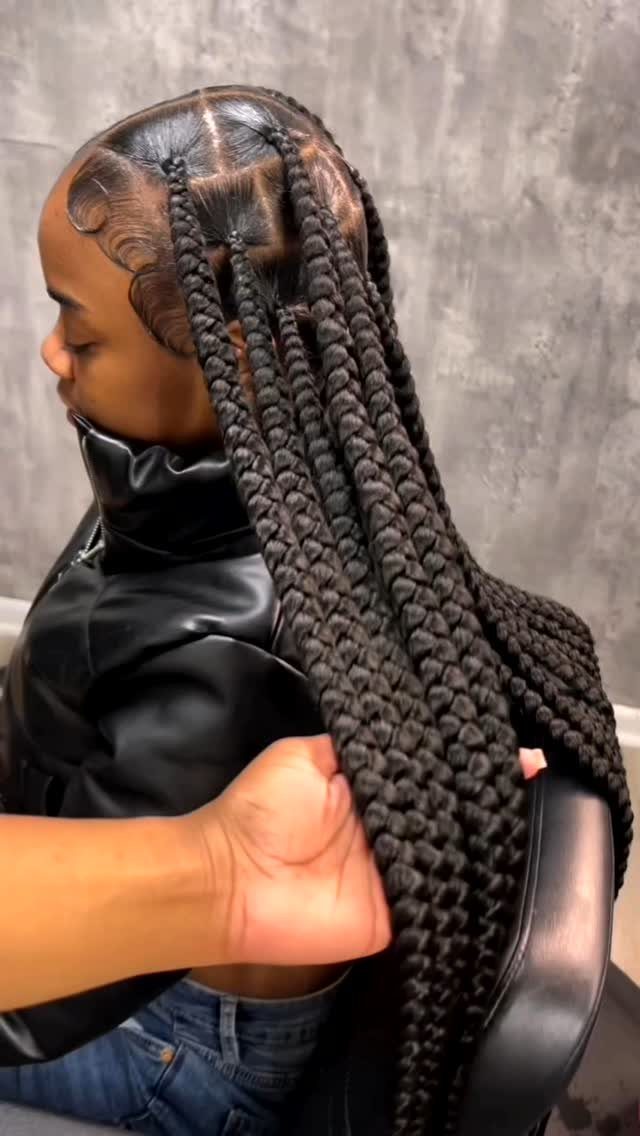 Person with thick black jumbo braids wearing a black leather jacket