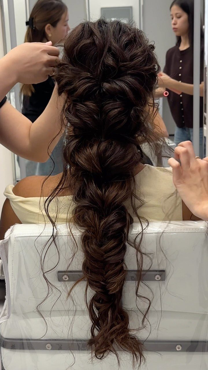 Voluminous brown mermaid braid cascading down a person's back in a hair salon.