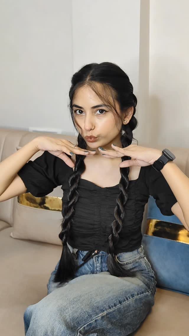Woman with long dark hair styled in two thick rope braids over shoulders