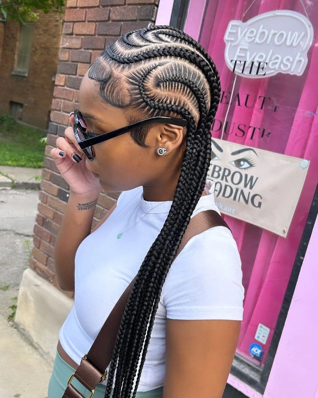 Woman with curved black stitch braids and long extensions wearing a white shirt.