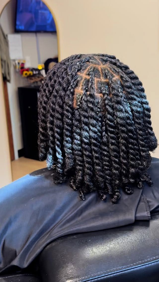 Black hair styled in thick two-strand twists with a geometric scalp pattern.