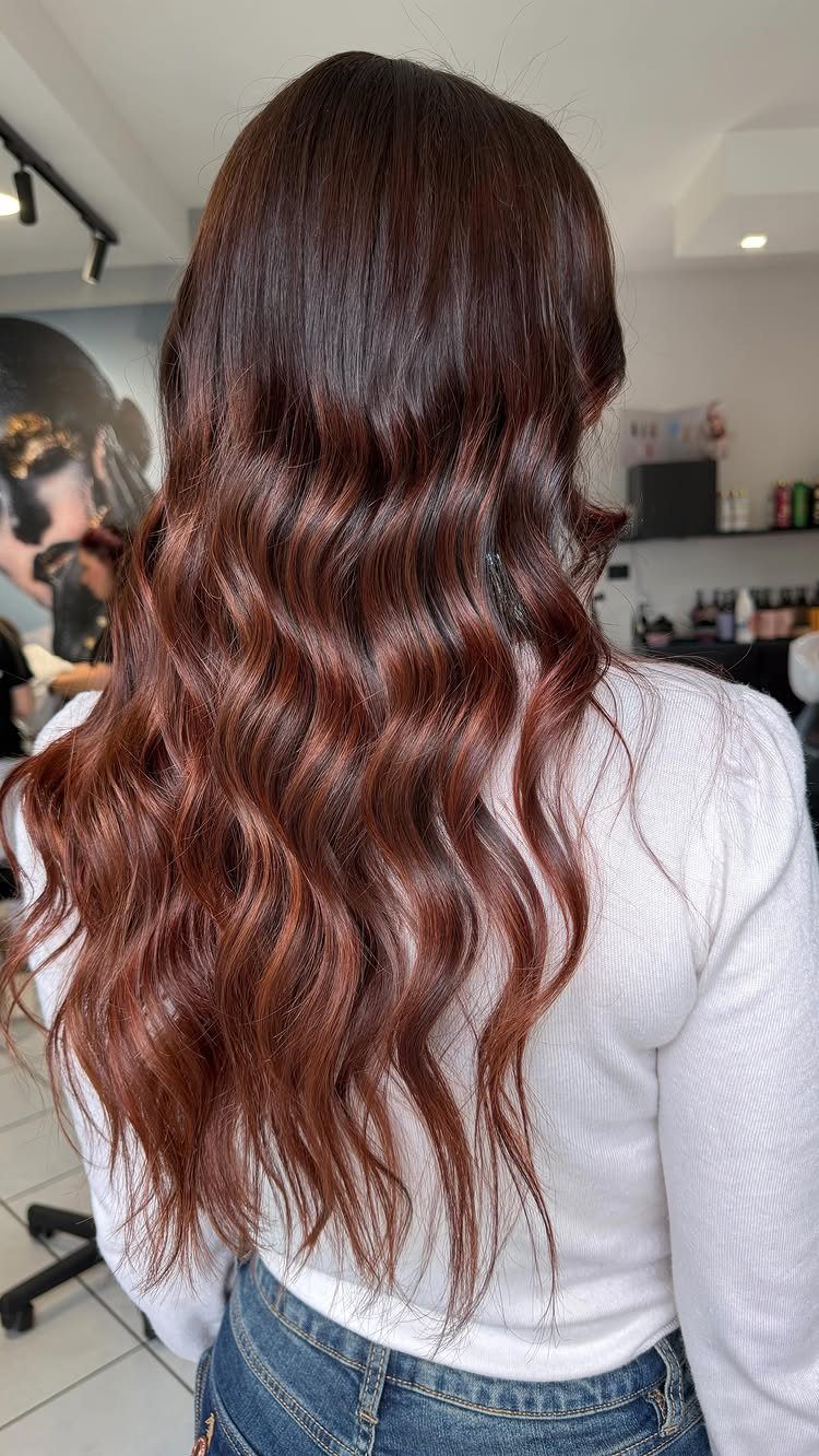 Long wavy dark brown hair with warm auburn highlights from a back view.