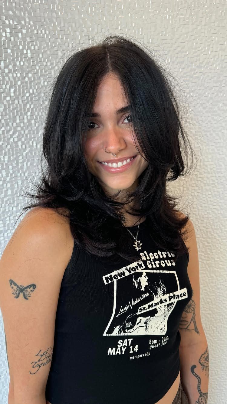Woman with medium length black shag haircut and layered style smiling for camera