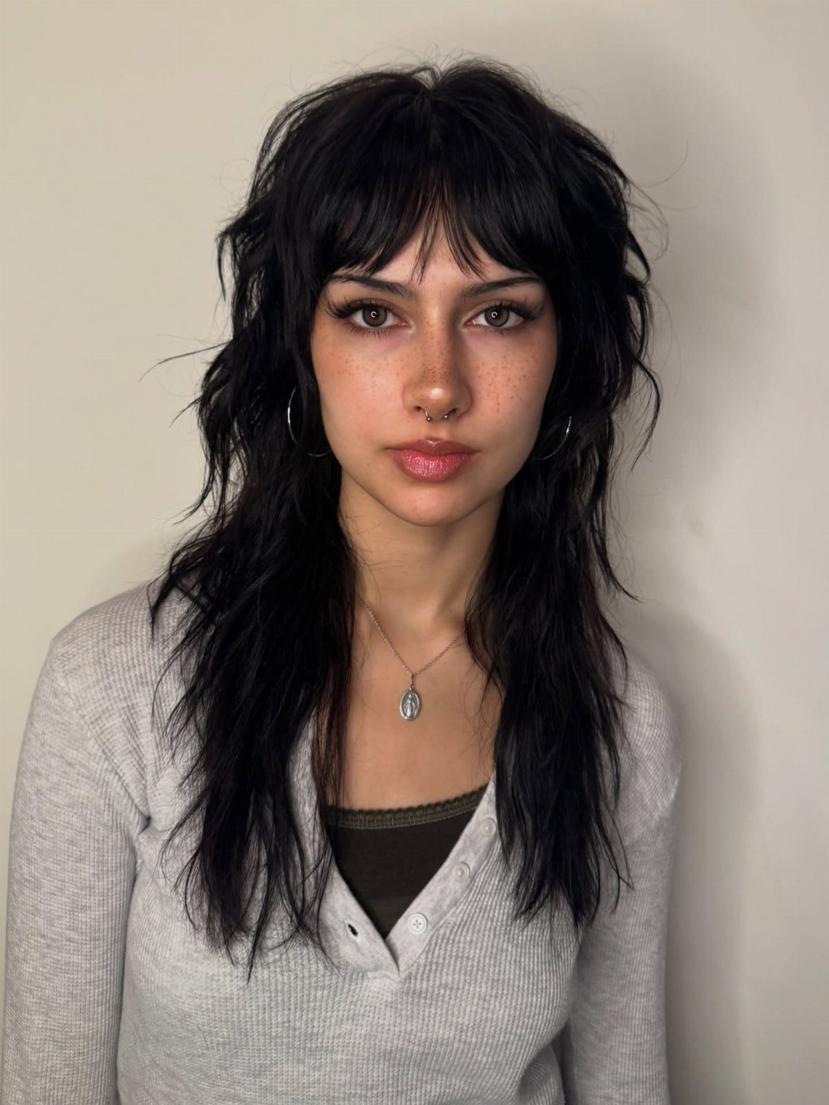 Woman with a black medium length edgy rock-inspired shag haircut and bangs.