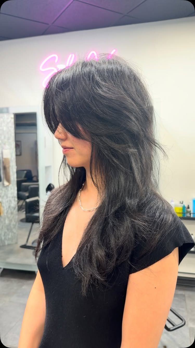 Woman with a medium length dark shag haircut and face-framing layers in a salon.