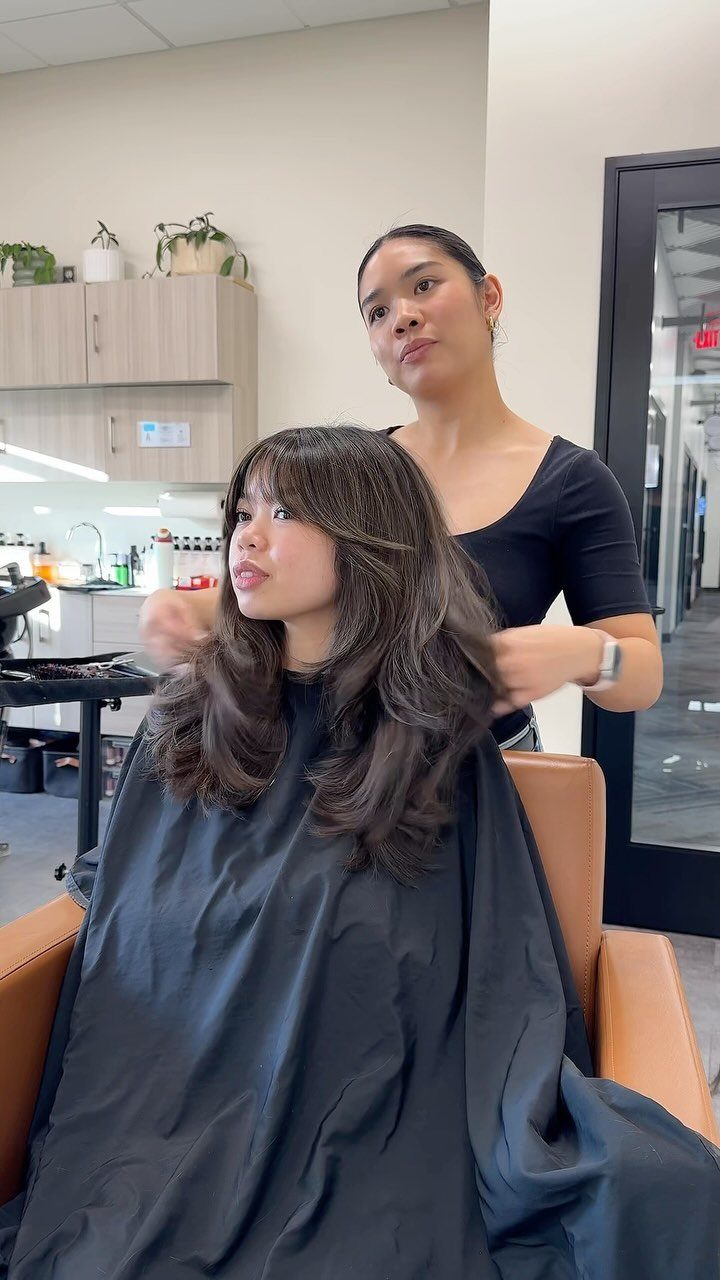 Woman with medium length brown shag haircut and curtain bangs in a salon