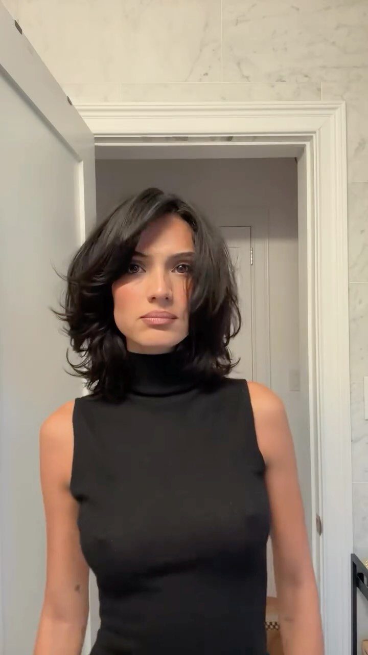 Woman with a smooth, polished medium length shag haircut and dark hair.
