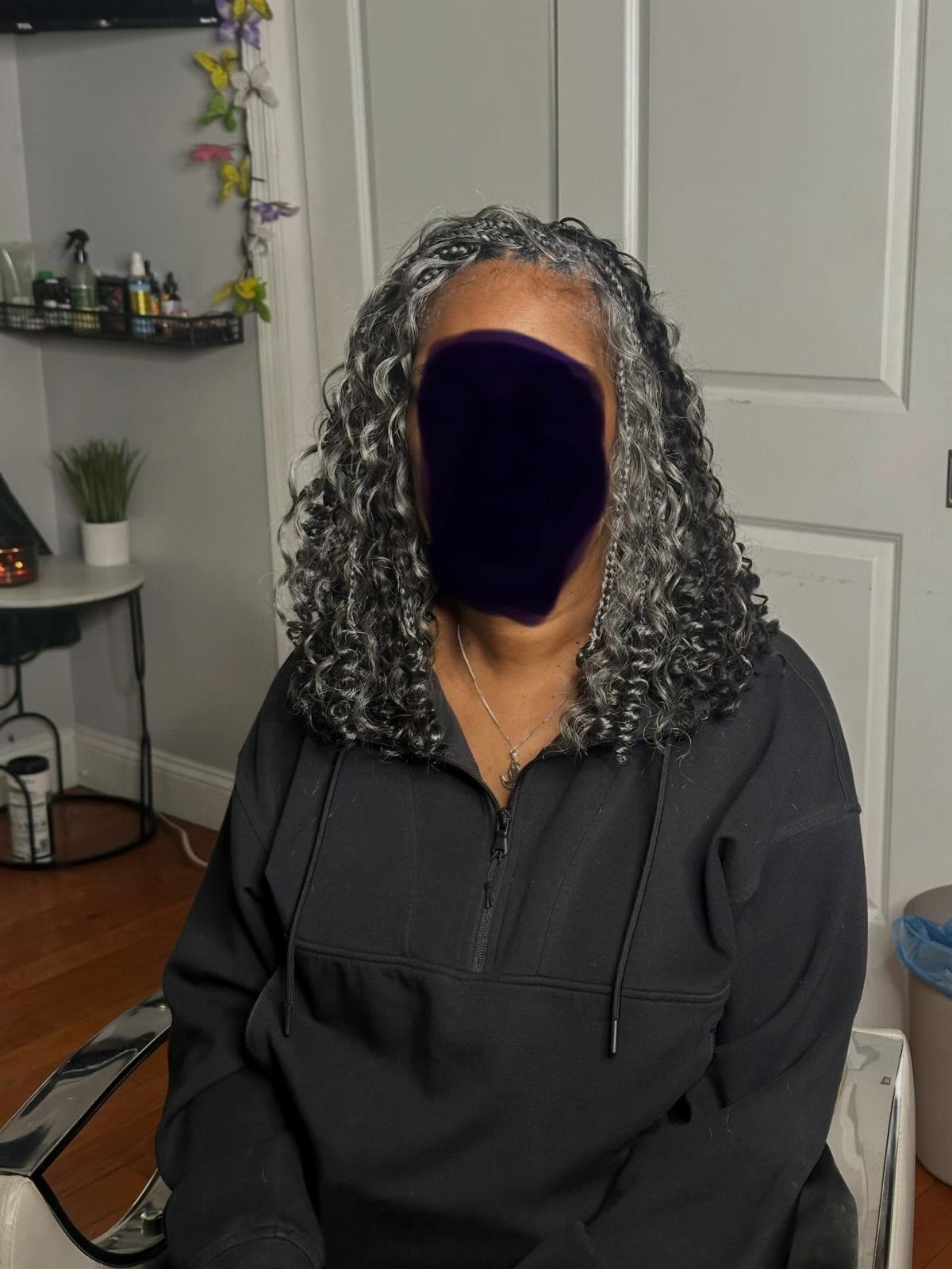 Woman with curly grey and silver shoulder-length hair wearing a black sweatshirt.